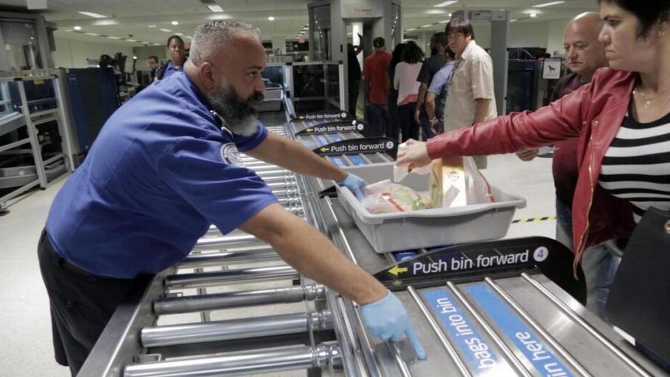 Un agente de TSA chequea el equipaje de mano de los pasajeros en las nuevas líneas rápidas de seguridad de AA en el Aeropuerto Internacional de Miami.