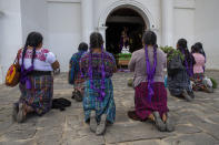 FILE - In this March 20, 2020 file photo, Kaqchikel indigenous women pray toward a statue of Jesus outside a Catholic church that was closed to help stop the spread of the new coronavirus in San Martin Jilotepeque, Guatemala. Many of the wealthy in Latin America are already recovering from coronavirus and experts are warning that the virus could kill untold numbers in the poorest sectors of society, where not working means not eating, people live packed together and few have access to healthcare, let alone sophisticated medical care. (AP Photo/Moises Castillo, File)