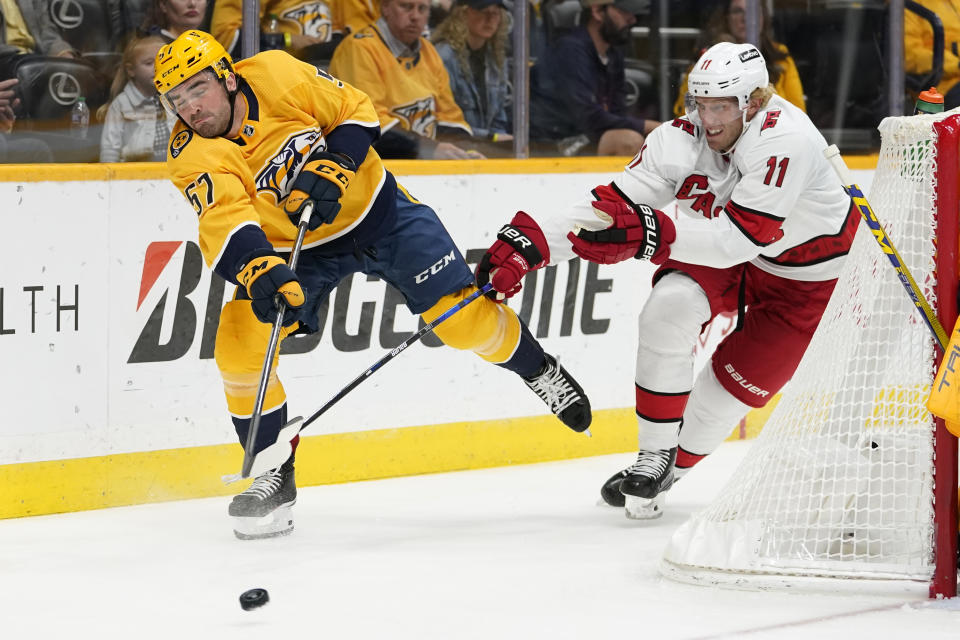 Nashville Predators defenseman Dante Fabbro (57) passes the puck past Carolina Hurricanes center Jordan Staal (11) in the first period of an NHL hockey game Saturday, Oct. 16, 2021, in Nashville, Tenn. (AP Photo/Mark Humphrey)