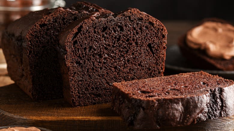 A sliced chocolate pound cake on a wooden board