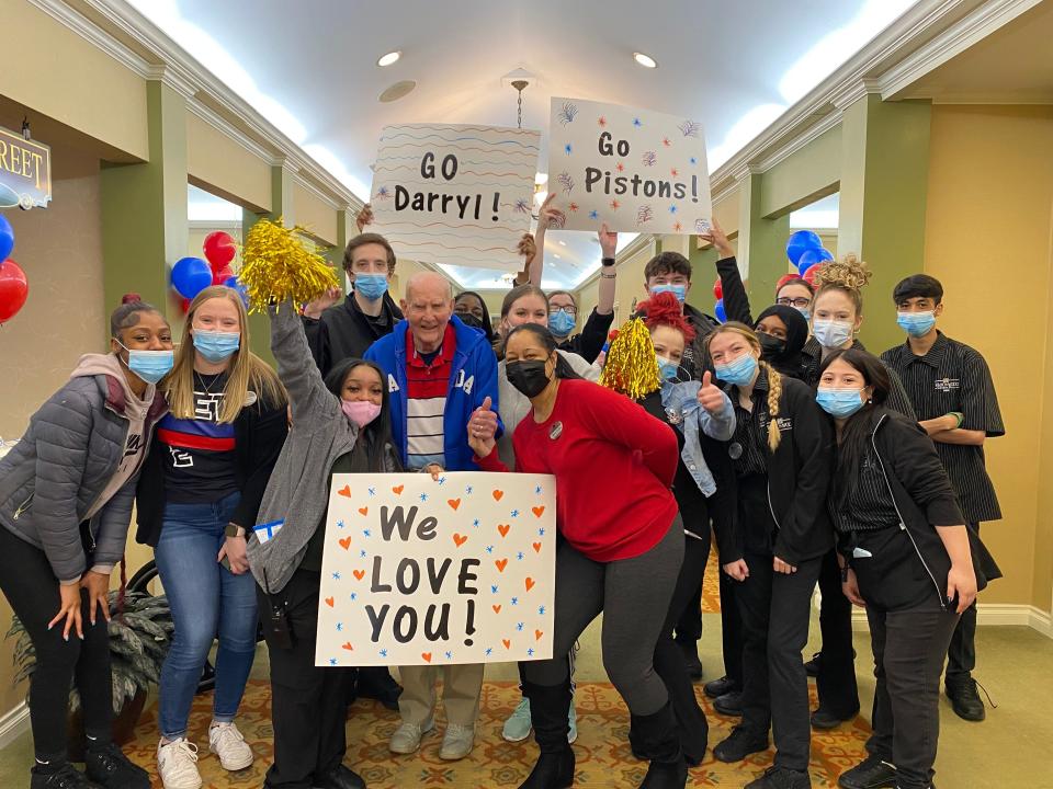 Darryl Raymond, 95, poses with the staff of Waltonwood Cherry Hill senior living facility in Canton, Michigan, on March 13, 2023. Raymond was surprised with a courtside experience to watch his favorite team, the Detroit Pistons, through the facility's Adventures by Waltonwood program.