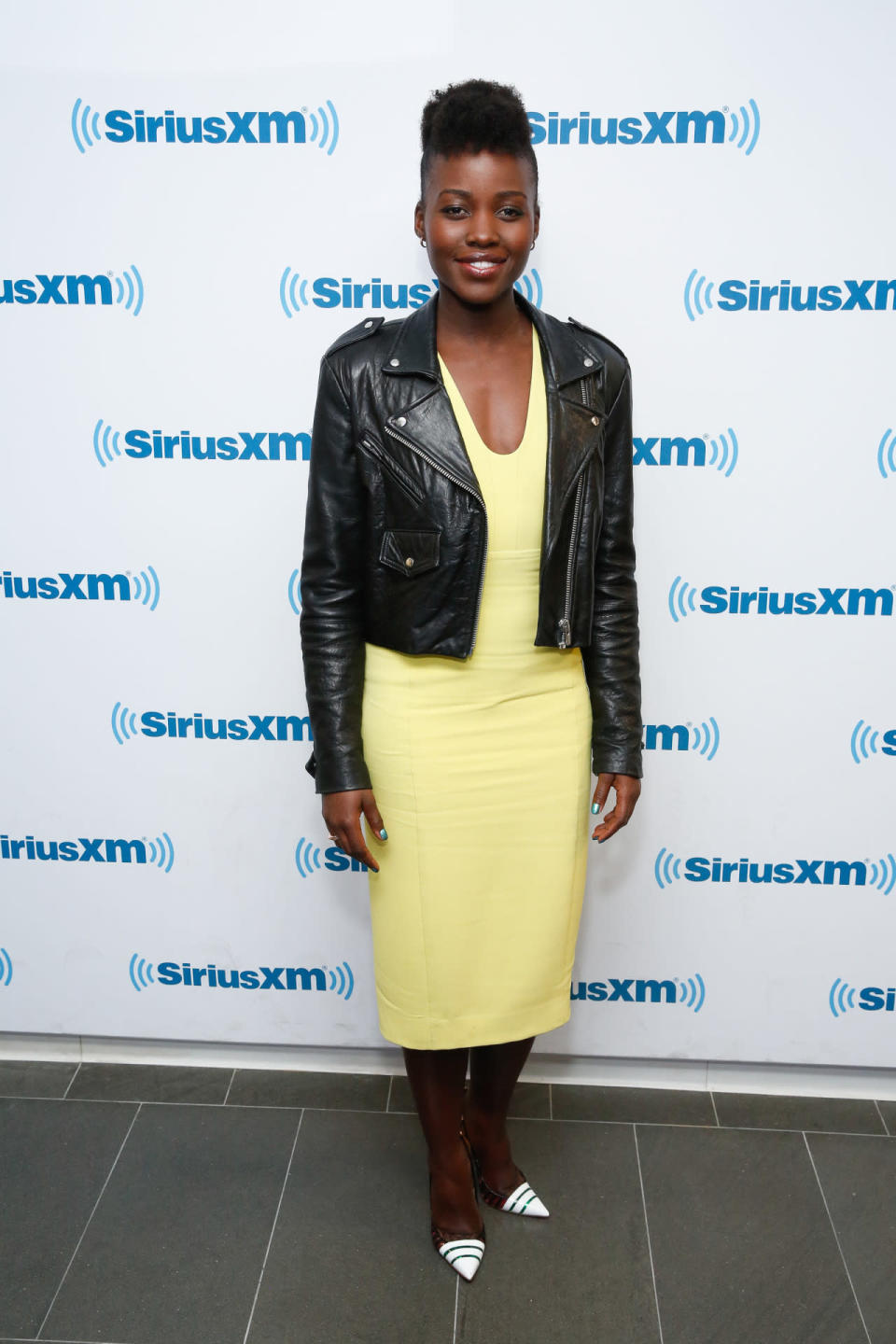 Lupita Nyong’o in a yellow dress with leather jacket at Sirius Radio. 