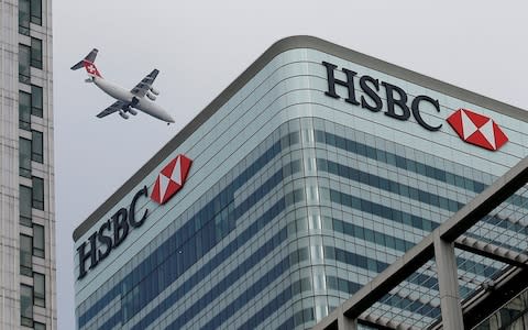 An aircraft flies past the HSBC headquarters building in the Canary Wharf financial district in east London - Credit: Peter Nicholls/REUTERS