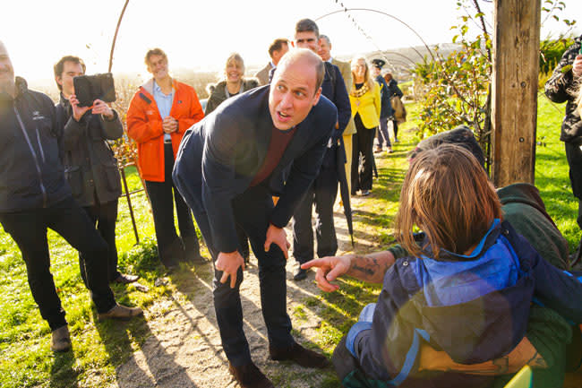 william bends down to speak to a small child in a garden