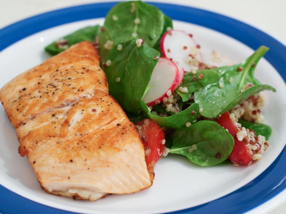 plate of salmon, spinach, radish slices, and quinoa