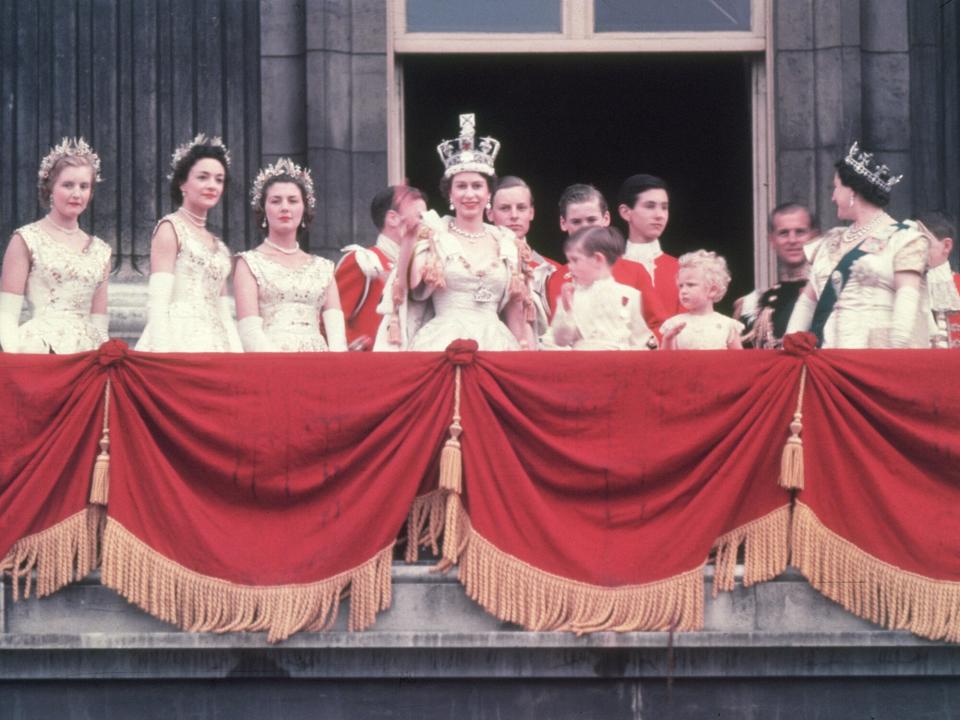 The newly crowned Queen Elizabeth II waves to the crowd from the balcony at Buckingham Palace. Her children Prince Charles and Princess Anne stand with her