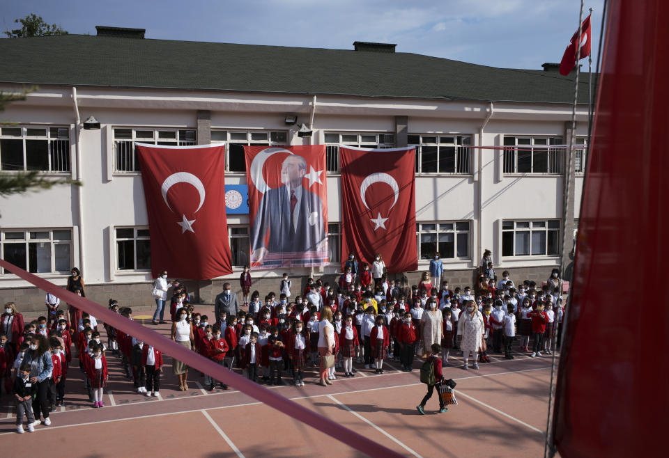 Pupils and teachers stand to sing the Turkish national anthem before the first classes as they arrive back at Cankaya Primary School in Turkish capital Ankara as schools reopen after 18 months' closure due to COVID-19, Monday, Sept. 6, 2021. The Turkish government has decided to reopen schools and colleges in the country of 84 million - one of the world's youngest with 18 million students.(AP Photo/Burhan Ozbilici)