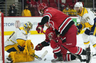 Carolina Hurricanes center Martin Necas (88) and right-wing Jesper Fast (71) try to score against Nashville Predators goaltender Juuse Saros (74) while defenseman Mattias Ekholm (14) looks on at right during the second period of an NHL hockey game in Raleigh, N.C., Saturday, April 17, 2021. (AP Photo/Gerry Broome)