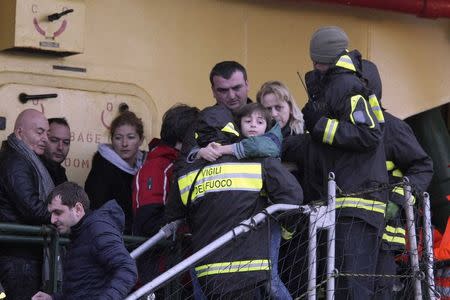 A firefighter carries a child from the "Spirit of Piraeus " cargo container ship as they arrive at Bari harbour, after the car ferry Norman Atlantic caught fire in waters off Greece December 29, 2014. REUTERS/Stringer