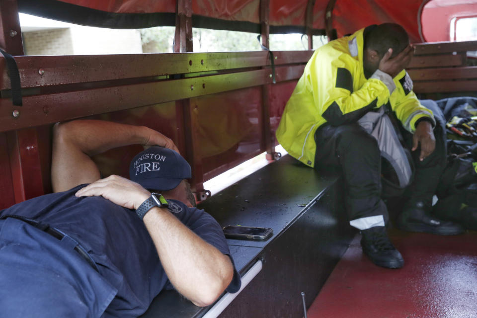 Houston firefighters Aaron Bond, left, and Trent Laday rest in a high-water rescue vehicle between calls around noon Tuesday, Sept. 22, 2020, at HFD station 46 in Houston. The pair said they received their first water-rescue calls around 4 a.m. Bond said he had been working since 6 a.m. Monday. (Jon Shapley/Houston Chronicle via AP)