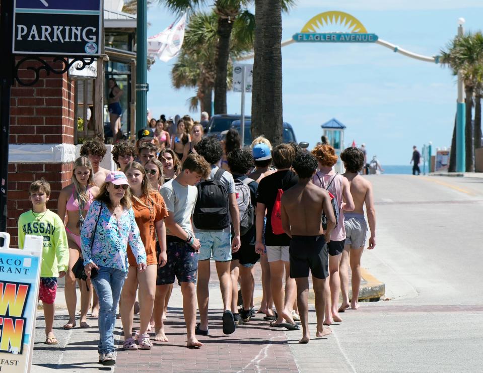 Spring Breakers along with families share the sidewalk along Flagler Avenue in New Smyrna Beach, Thursday, March 15, 2023 