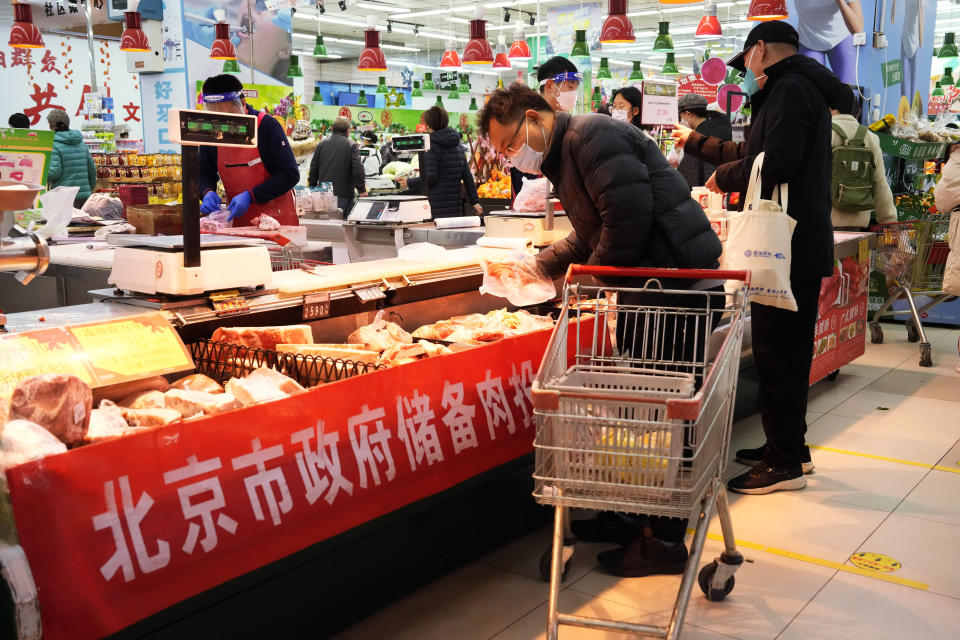 A man wearing a mask shops for meat near a banner which reads "Beijing Government Reserve Meat" for sale at a supermarket in Beijing, Saturday, Nov. 26, 2022. (AP Photo/Ng Han Guan)