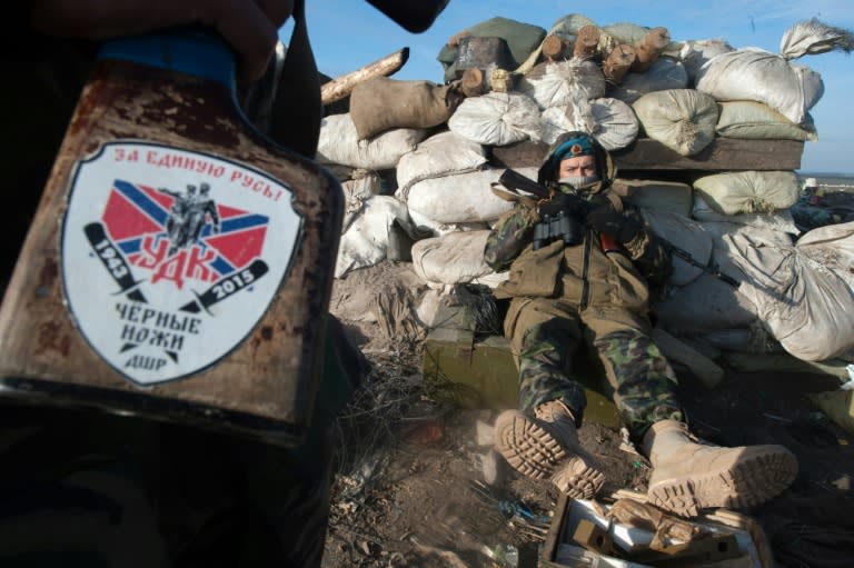 A pro-Russian rebel holds a rifle with the emblem of the unit "Black knife" that reads "For united Rus" as another rests