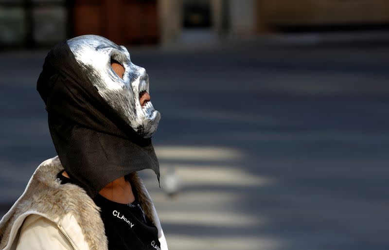 A person wearing a mask walks down a street in Vienna