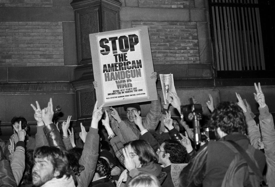 John Lennon fans continue their vigil outside the Dakota apartment building in New York, Dec. 10, 1980, chanting for peace, raising their hands with the peace sign and protesting current gun control laws, all the while listening to Beatles' music. (AP Photo/David Bookstaver)