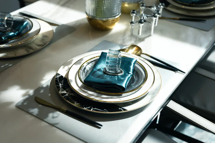 Elegant table setting with plates, silverware, and a folded napkin under natural light