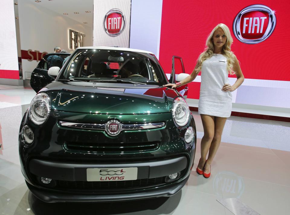 A model poses next to Fiat 500 L Living car during a media preview day at the Frankfurt Motor Show