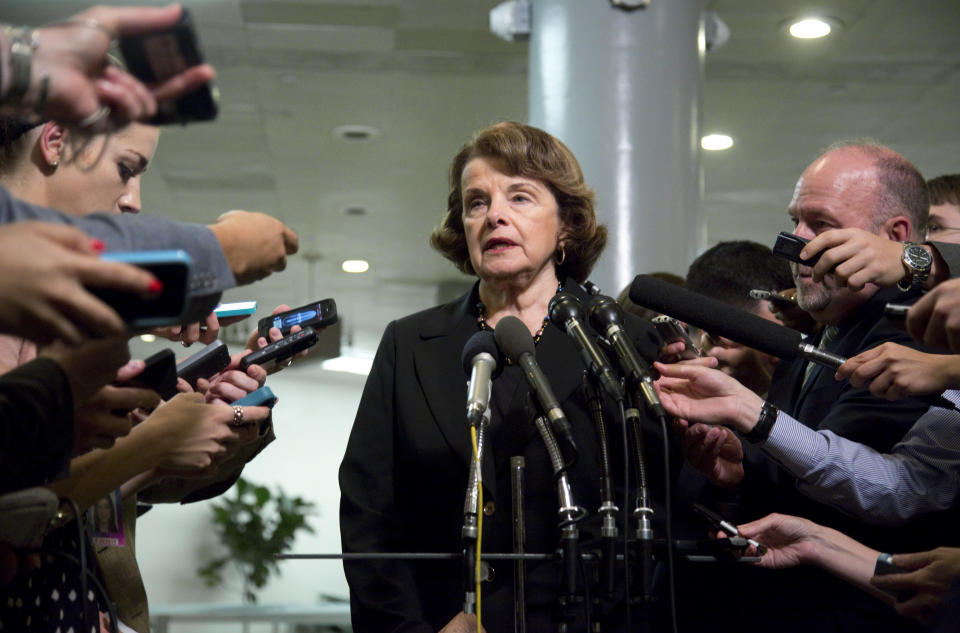 Sen. Dianne Feinstein surrounded by reporters holding microphones and cellphones.