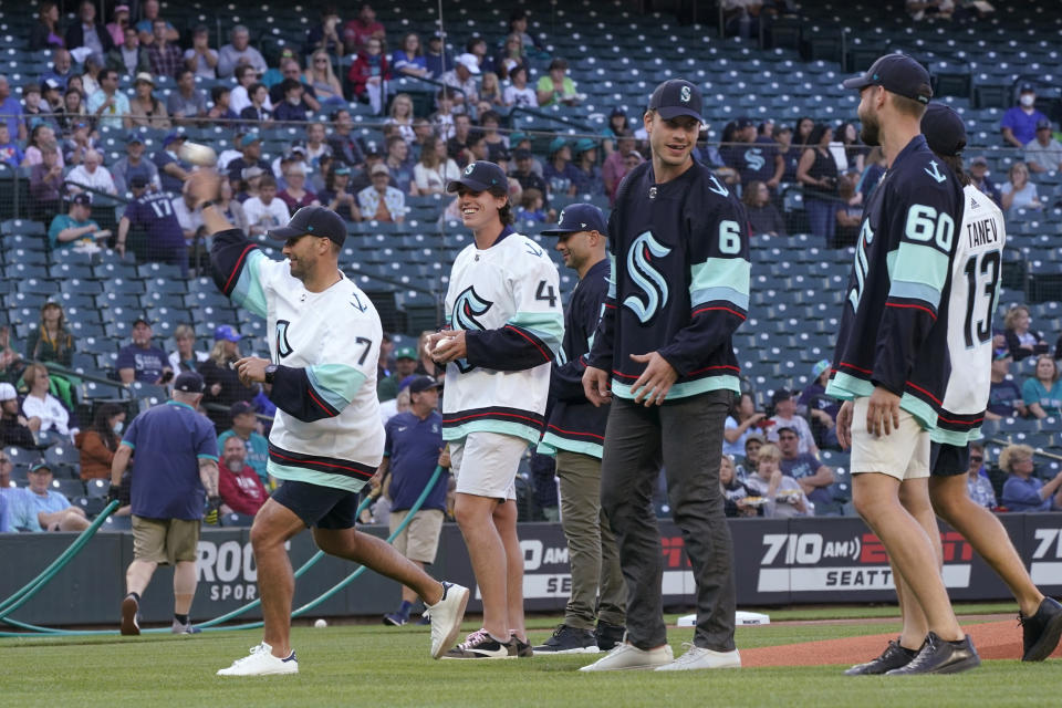 Seattle Kraken forward Jordan Eberle, left, throws out a first pitch as teammates watch before a baseball game between the Seattle Mariners and the Oakland Athletics, Thursday, July 22, 2021, in Seattle. Eberle was selected by the Kraken on Wednesday from the New York Islanders in the NHL expansion draft. (AP Photo/Ted S. Warren)