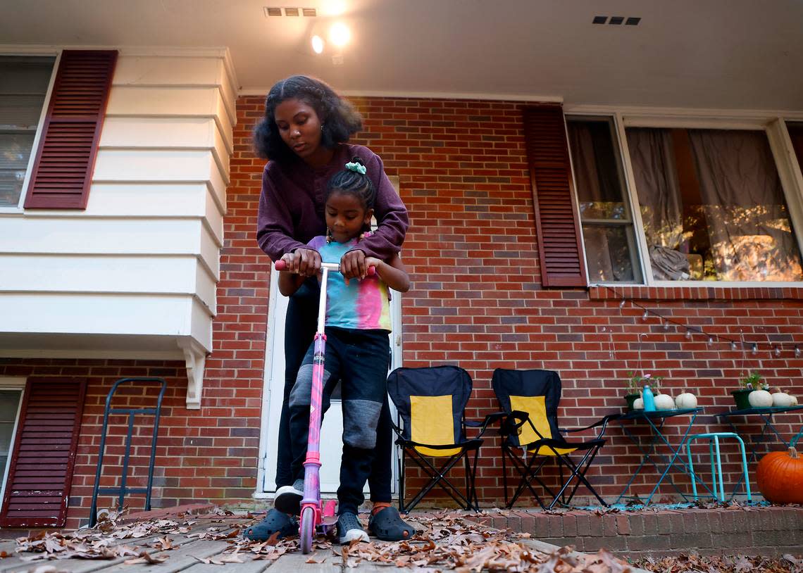 Sheba Everett helps her daughter, Hannah Edgerton, 5, put away a scooter after taking it for a ride near their home in Durham, N.C. on Thursday, Nov. 3, 2022.
