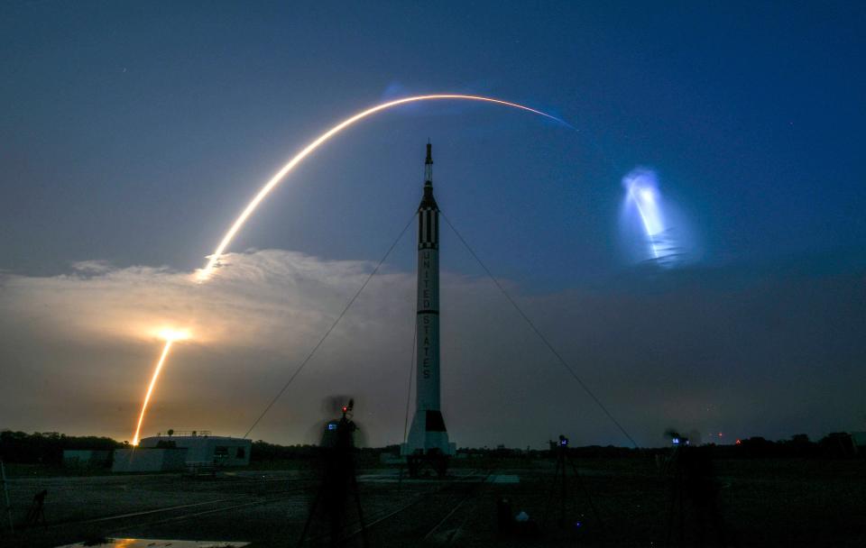 A SpaceX Falcon 9 rocket is seen taking Starlink satellites to orbit from Kennedy Space Center in May 2022. In the foreground is a Mercury-Redstone rocket replica at Cape Canaveral's Launch Complex 5.