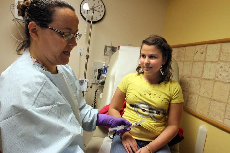 In a 2016 file photo, Gisela Carrier, then 12, receives her weekly chemotherapy from her primary nurse, Angi Hastings.