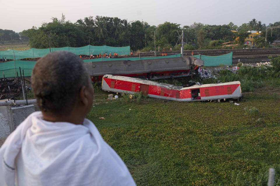 A Hindu priest looks at the mangled wreckage of the two passenger trains that derailed Friday in Balasore district, in the eastern Indian state of Orissa, Monday, June 5, 2023. The derailment in eastern India that killed over 200 people and injured hundreds was caused by an error in the electronic signaling system that led a train to wrongly change tracks and crash into a freight train, officials said Sunday. (AP Photo/Rafiq Maqbool)
