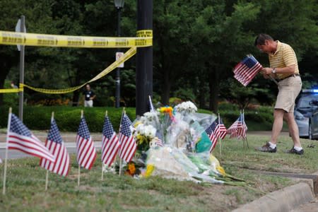 Local resident Rich Lindgren places flags at a makeshift memorial outside a municipal government building where a shooting incident occurred in Virginia Beach, Virginia