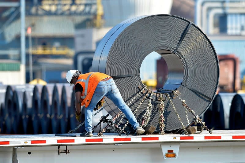 <cite>美國肯塔基州根特市的Nucor鋼鐵廠，工人將一卷鋼材固定到平板卡車上。（AP）</cite>
