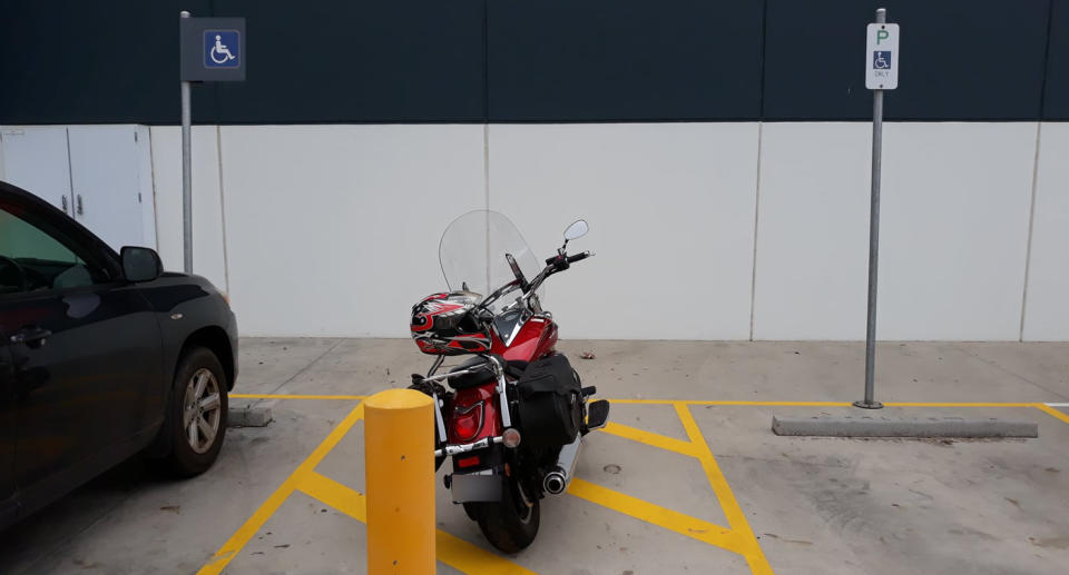 A motorcycle parked between two disability parking bays in a Victorian Bunnings carpark