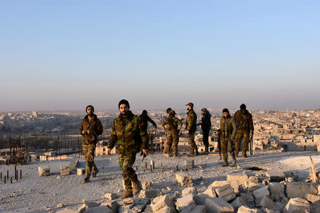 Syrian government soldiers walk near a general view of eastern Aleppo after they took control of al-Sakhour neigbourhood in Aleppo, Syria in this handout picture provided by SANA on November 28, 2016. SANA/Handout via REUTERS