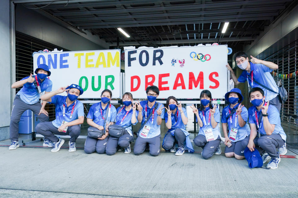 TOKYO, JAPAN - JULY 25: Japanese volunteers with a sign that says one team for our dreams competing on Women's Road Race during the Tokyo 2020 Olympic Games at the Fuji International Speedway on July 25, 2021 in Tokyo, Japan (Photo by Ronald Hoogendoorn/BSR Agency/Getty Images)