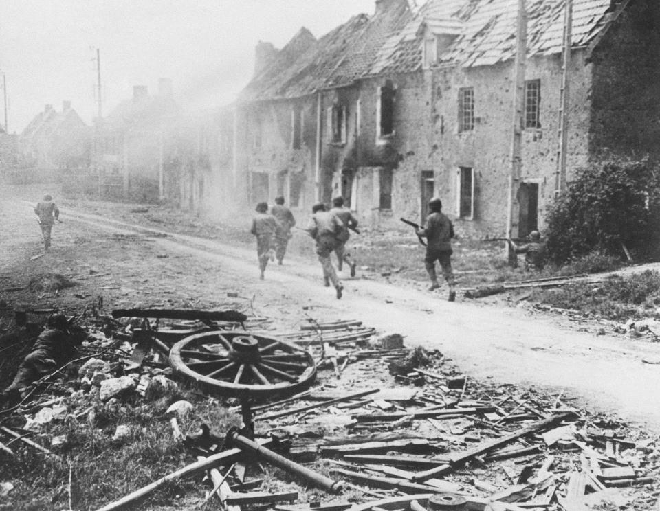 FILE - American infantrymen sprint down a village street in Normandy, July 27, 1944. The D-Day invasion that helped change the course of World War II was unprecedented in scale and audacity. Veterans and world dignitaries are commemorating the 79th anniversary of the operation. (Pool via AP, File)