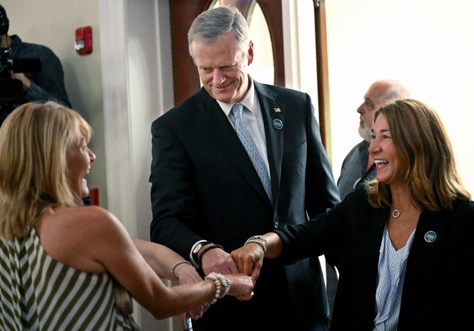 Gov. Charlie Baker,  Lt. Gov. Karyn Polito  and Janet Leombruno, left, Karen Foran Dempsey's sister, compare bracelets given to attendees of the Karen Foran Dempsey Ballroom Naming Ceremony at Framingham's Village Hall, July 26, 2022.   People with mobility challenges can now access the ballroom due to Dempsey's push to add an elevator to reach the second floor.  