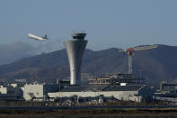 A plane takes off behind the air traffic control tower at San Francisco International Airport during the coronavirus outbreak in San Francisco, Tuesday, Nov. 24, 2020. (AP Photo/Jeff Chiu)