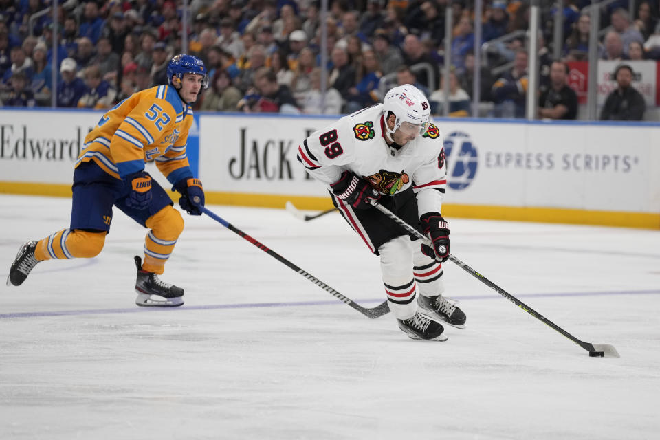 Chicago Blackhawks' Andreas Athanasiou (89) brings the puck down the ice as St. Louis Blues' Noel Acciari (52) defends during the third period of an NHL hockey game Thursday, Dec. 29, 2022, in St. Louis. (AP Photo/Jeff Roberson)
