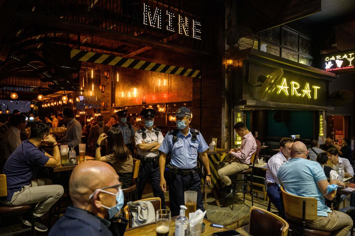 Food and Environmental Hygiene Department officers and police leave after inspecting the license of a restaurant and bar after it reopened, in Lan Kwai Fong, a popular drinking area in Hong Kong on April 29, 2021, as Covid-19 coronavirus social-distancing restrictions on restaurants and bars were eased under new vaccine bubble rules. (Photo by ANTHONY WALLACE / AFP) (Photo by ANTHONY WALLACE/AFP via Getty Images)