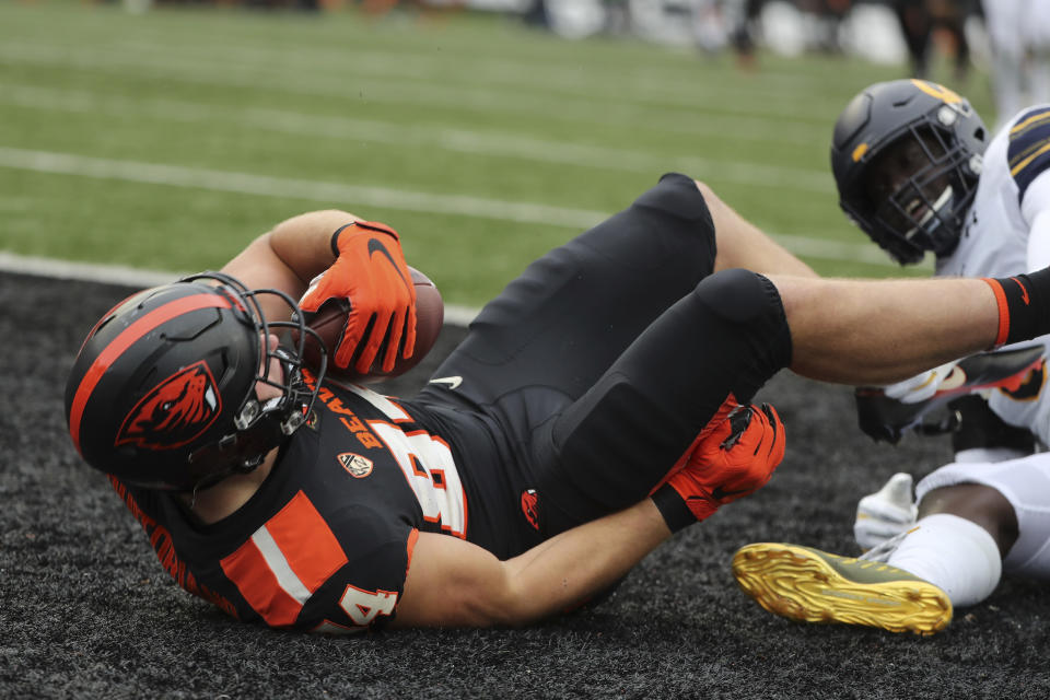 Oregon State tight end Teagan Quitoriano (84) is brought down in the end zone by California inside linebacker Kuony Deng (8) to score a touchdown on a pass from Oregon State quarterback Tristan Gebbia (3) during the first half of an NCAA college football game in Corvallis, Ore., Saturday, Nov. 21, 2020. (AP Photo/Amanda Loman)