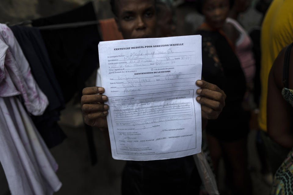 Lovely Benjamin, who was sexually assaulted by a gang member, holds up her medical report, in Jean-Kere Almicar's front yard, where she and her young son have sought refuge, in Port-au-Prince, Haiti, Sunday, June 4, 2023. Gangs torched the items she used to sell, including rice and oil. While she and her 4-year-old son survived the attack in Cite Soleil, gangs killed her partner and set his body on fire. (AP Photo/Ariana Cubillos)