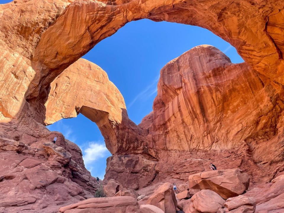 People climb rocks at the windows section of Arches National Park.