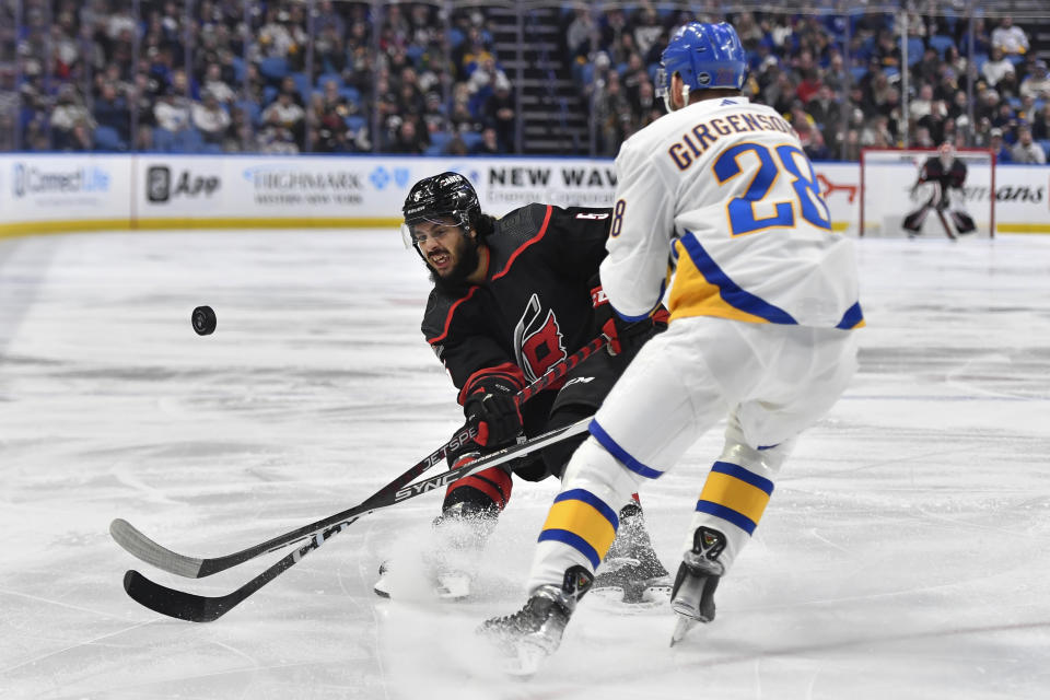 Carolina Hurricanes defenseman Jalen Chatfield, left, clears the puck away from Buffalo Sabres left wing Zemgus Girgensons during the first period of an NHL hockey game in Buffalo, N.Y., Wednesday, Feb. 1, 2023. (AP Photo/Adrian Kraus)