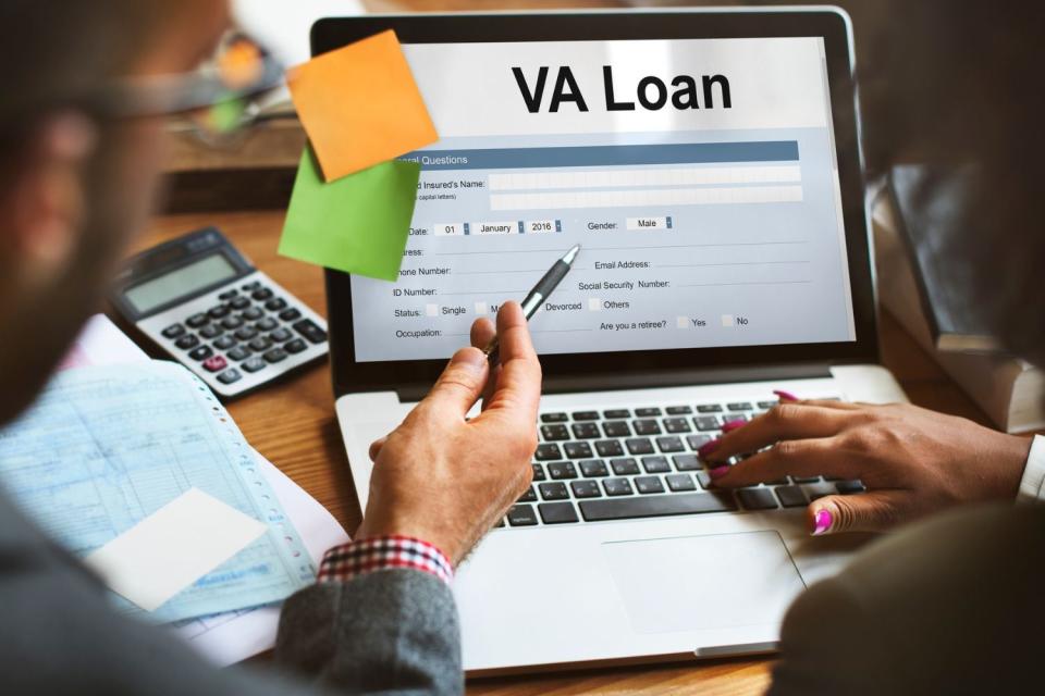 Two people gesture while looking at a screen with 'VA Loan' written on it.
