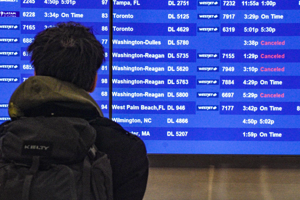 A passenger check flight departure schedules, some showing cancellations, at the Delta terminal at Laguardia Airport, Friday Dec. 23, 2022, in New York. (AP Photo/Bebeto Matthews)