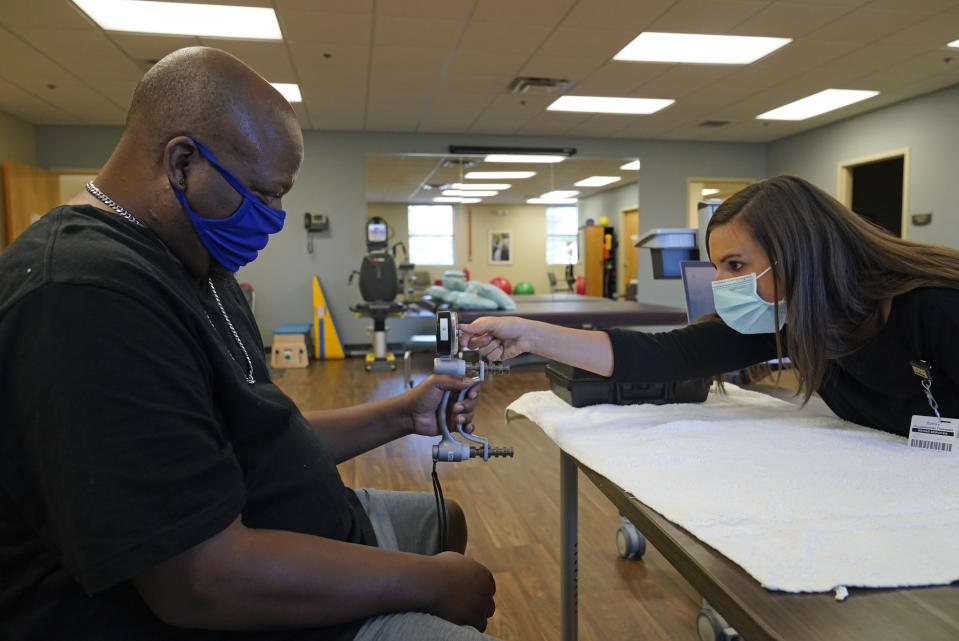 Emily Smith tests Larry Brown's hand strength during an occupational therapy session at Community Health Network, Thursday, Aug. 20, 2020, in Indianapolis. His hands _ which helped make him Indiana State's eighth all-time receiving leader _ can’t even open a can of soda. (AP Photo/Darron Cummings)