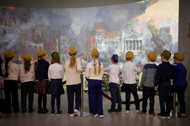 Several classes of primary school children wearing military caps and orange-and-black Saint George's ribbons listen to stories about the Red Army's victory in 1945 (Natalia KOLESNIKOVA)