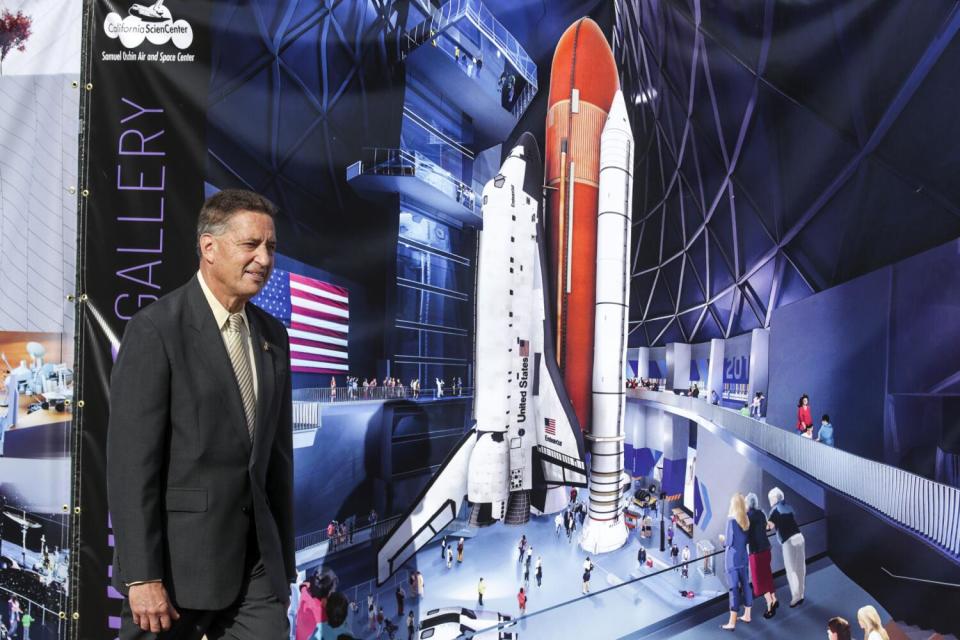 A man stands next to a display of a Space Shuttle exhibit.