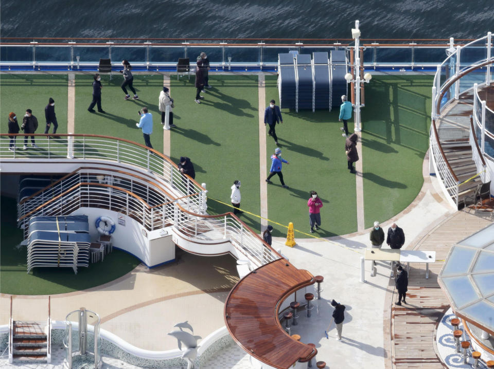 Masked passengers are seen on the deck of the cruise ship Diamond Princess docked at Yokohama Port, near Tokyo, Friday, Feb. 7, 2020. Japan on Friday reported 41 new cases of a virus on the cruise ship that's been quarantined. About 3,700 people have been confined aboard the ship. (Sadayuki Goto/Kyodo News via AP)