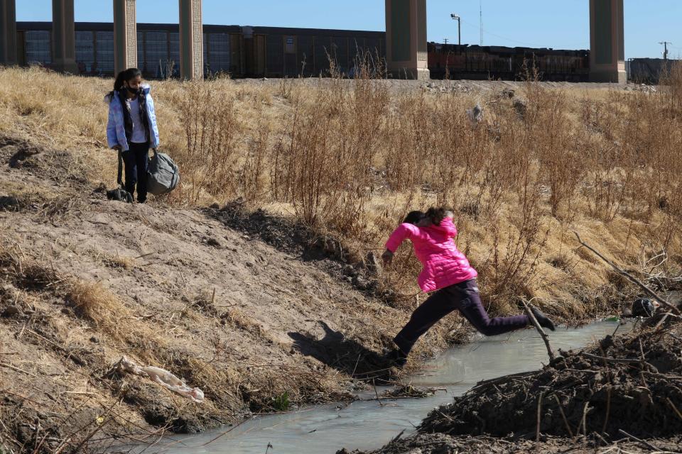 A migrant girl jumps to cross the Rio Bravo to get to El Paso, Texas, from Ciudad Juarez, Mexico, on February 5, 2021. / Credit: HERIKA MARTINEZ/AFP via Getty Images