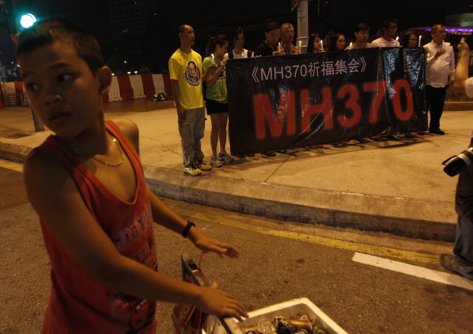 Malaysian ethnic Chinese hold candles and banner before candlelight vigil for passengers of the missing plane at a prominent street junction near Independence Square in Kuala Lumpur