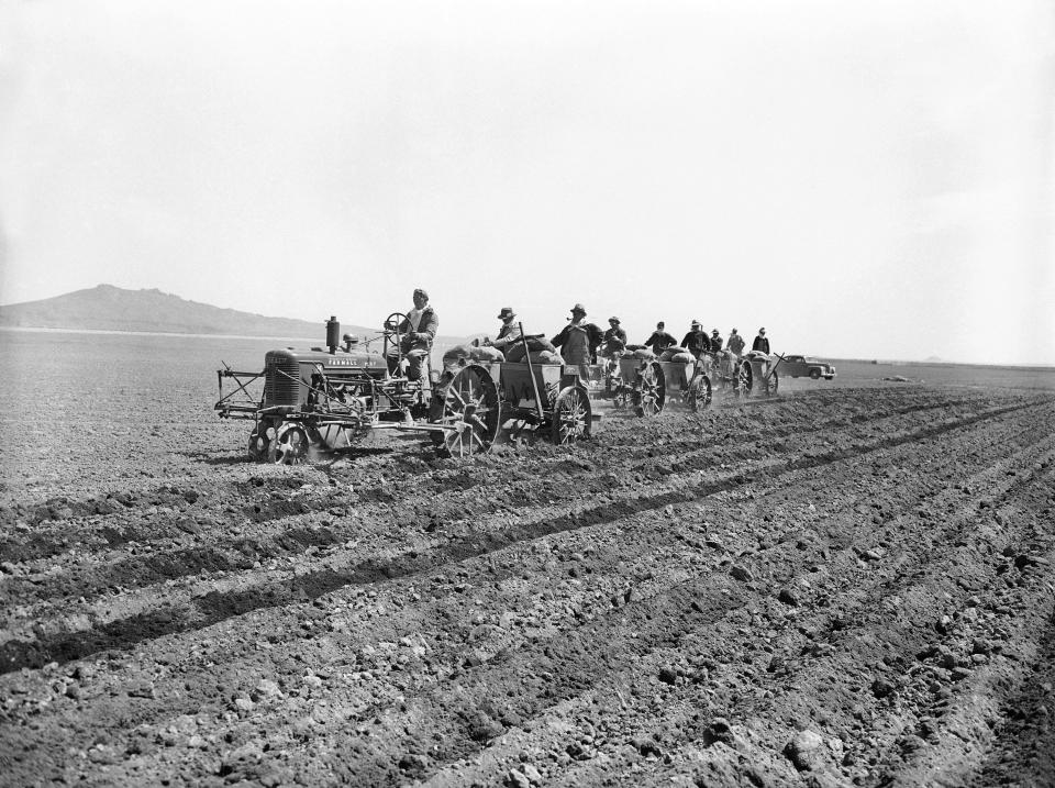 FILE - In this May 22, 1943, file photo, using light tractors, Japanese residents of their Relocation Center at Tule Lake California, begin planting potatoes in the several hundred acres of fertile soil of reclaimed old Tule Lake. Amid commemorations of Wednesday's 75th anniversary of the formal Sept. 2, 1945, surrender ceremony that ended World War II, Hidekazu Tamura, a former Japanese-American living in California, has vivid memories of his time locked up with thousands of other Japanese Americans in U.S. internment camps. Torn between two warring nationalities, the experience led him to refuse a loyalty pledge to the United States, renounce his American citizenship and return to Japan. During the pacific war period, Tamura was at Tule Lake, a segregation center for those deemed disloyal.(AP Photo, File)